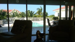Una habitación con vistas a una piscina, dos sillones y una estatua decorativa de un caballo.