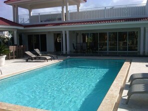 A rectangular swimming pool with clear blue water, surrounded by lounge chairs and a covered patio area. - Vacation Villa Gated Only Minutes From Downtown (Sosúa)