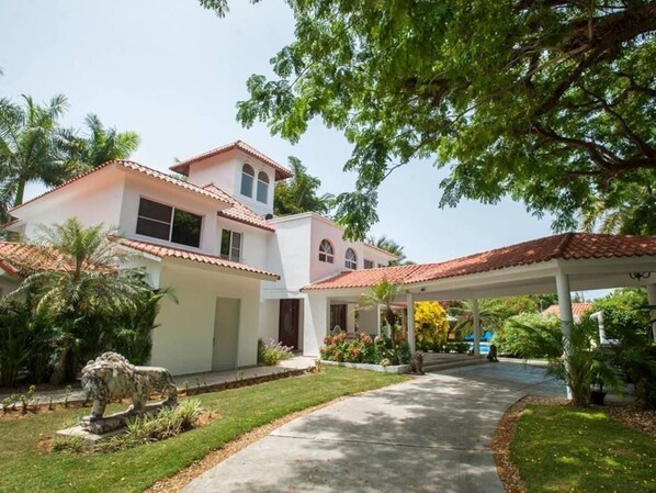 A two-story house with a covered patio area and a stone lion statue in the front yard.