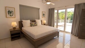 A spacious bedroom with a large bed, two bedside tables with lamps, a ceiling fan, and a view of a balcony. - Private 3 Bedroom Villa Near Walking Trail (Sosúa)