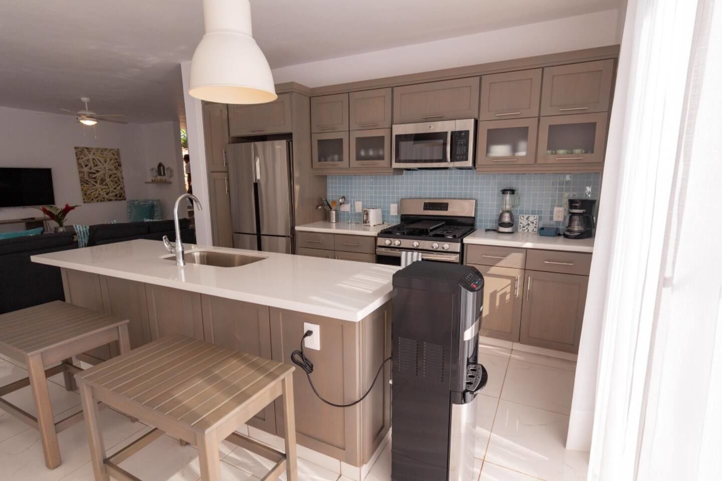 A modern kitchen with a central island, stainless steel appliances, and light-colored cabinetry.