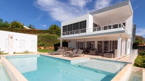 A modern two-story house with a swimming pool, outdoor seating, and a landscaped garden. - Private 3 Bedroom Villa Near Walking Trail (Sosúa)