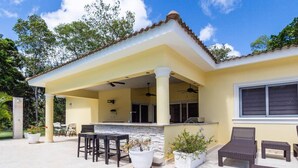 A covered patio with outdoor furniture, a stone fireplace, and a poolside bar. - Private and Spacious 5 Bedroom Villa (Sosúa)
