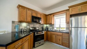 Una cucina moderna con mobili in legno, un frigorifero in acciaio inossidabile, un forno e un microonde.