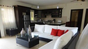 Een moderne woonkamer met een bank, salontafel en een keuken op de achtergrond.