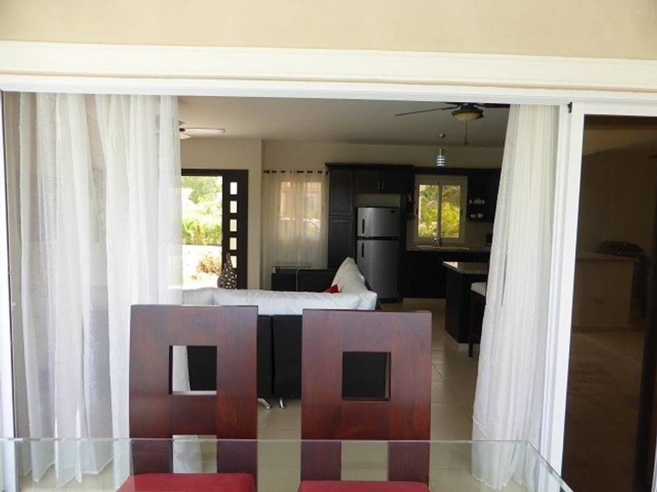 Een moderne woonkamer met een glazen scheidingswand, een eethoek met tafel en stoelen, en een keuken op de achtergrond.