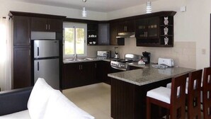 Een moderne keuken met donkere kastjes, een centraal eiland, roestvrijstalen apparatuur en hanglampen.