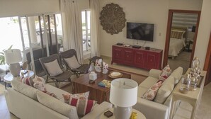 Un salon comprenant un canapé, des fauteuils, une table basse, un téléviseur et un meuble.