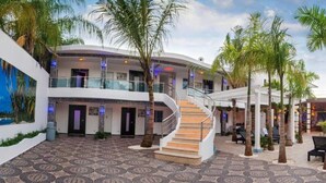 A hotel lobby with a patterned floor, a central staircase, and palm trees. - Luxury 14 Bedroom Villa Walking to Clubs/beaches! (Sosúa)
