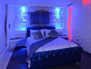 A modern bedroom with a bed, nightstands, and a wall with circular patterns. - Luxury 14 Bedroom Villa Walking to Clubs/beaches! (Sosúa)