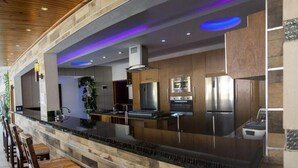 A modern kitchen with a stone countertop, wooden cabinets, and stainless steel appliances. - Luxury 14 Bedroom Villa Walking to Clubs/beaches! (Sosúa)