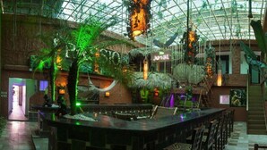 A spacious indoor area with a central bar, surrounded by lush greenery and a high ceiling with a glass structure. - Luxury 14 Bedroom Villa Walking to Clubs/beaches! (Sosúa)