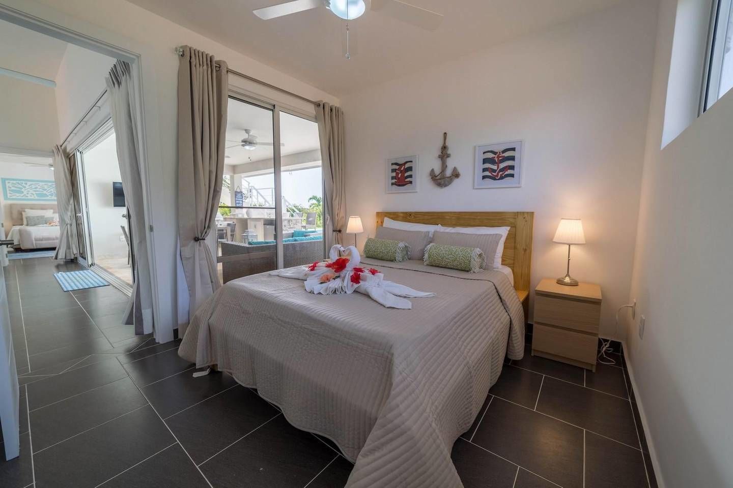 A hotel room with a bed, bedside lamps, a view of the pool, and a ceiling fan.