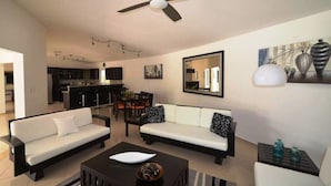 A modern living room with a sofa set, a coffee table, and a dining area with chairs.