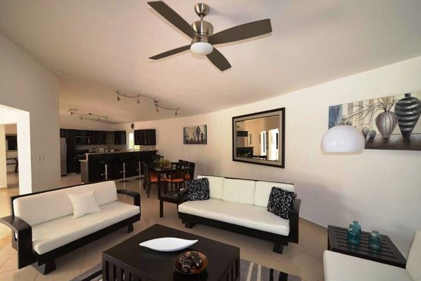 A modern living room with a sofa set, a coffee table, and a dining area with chairs.