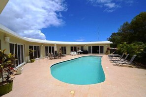 A pool area with a curved pool, lounge chairs, and a covered seating area.