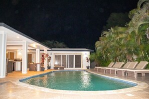 A modern pool area with a clear pool, lounge chairs, and a covered patio.