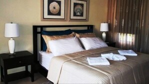 A hotel room with a bed, two nightstands, two lamps, and two framed pictures on the wall. - Two Bedroom With Jaccuzi Gated (Sosúa)