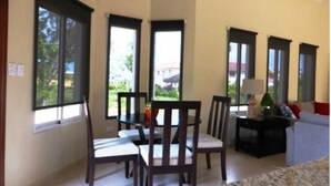 A living room with large windows, a dining area with chairs and a table, and a sofa. - Two Bedroom With Jaccuzi Gated (Sosúa)