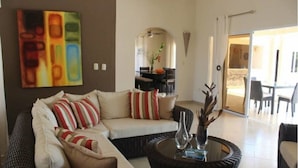 A living room with a sofa, coffee table, and a dining area in the background. - Villa With Jacuzzi, TVs in all Bedrooms (Sosúa)