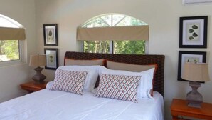 Une chambre avec un grand lit, deux tables de chevet, une fenêtre avec vue et des tableaux encadrés au mur.