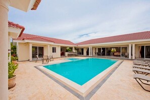 A pool area with a rectangular pool, lounge chairs, and covered seating areas. - Privacy and Comfort Luxury 6 Bedroom Villa (Sosúa)