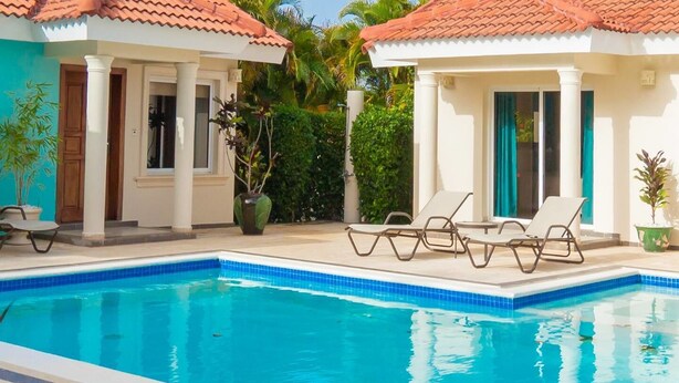A swimming pool with lounge chairs and a small building with a tiled roof. - Privacy and Comfort Luxury 6 Bedroom Villa (Sosúa)