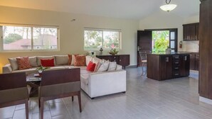 A spacious living area with a sofa set, dining table, and kitchen area with dark cabinets and a large island. - Villa Equipped With an Infinity Edged Pool in Gated Community (Sosúa)