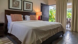 A hotel room with a large bed, two framed artworks above it, a nightstand, a lamp, and a view of the outdoors through a sliding door. - Villa Equipped With an Infinity Edged Pool in Gated Community (Sosúa)