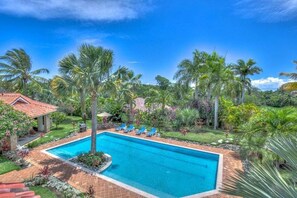 A swimming pool with lounge chairs, surrounded by palm trees and a garden. - Villa Jardin Paraiso Cabarete Villa Near the Beach (Cabarete)