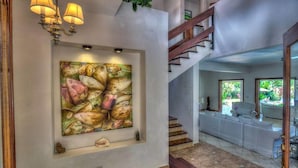 A hallway with a large abstract painting, a staircase, and a view of a pool area. - Villa Jardin Paraiso Cabarete Villa Near the Beach (Cabarete)