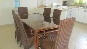 A glass-top dining table with wicker chairs in a kitchen with white cabinets and a water dispenser. - Hilltop Ocean View Villa w/ Large Pool Walking to Strip and Sosua Beach (Sosúa)