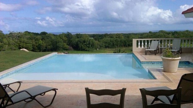 Una piscina con sillas de descanso y una mesa, rodeada por una terraza con vistas al paisaje.