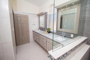 A modern bathroom with a large mirror, a sink, and a door.