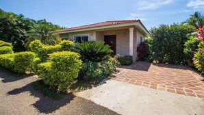 A two-story house with a tiled roof, surrounded by well-maintained gardens and a paved driveway. - Sunny Days and Tropical Nights Await you (Sosúa)