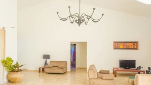 A spacious living room with a chandelier, two sofas, a TV, and a potted plant. - Private Villa With Pool in Sosua for Large Groups (Sosúa)