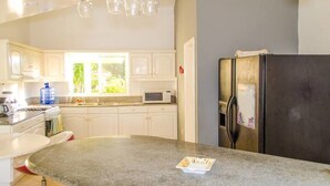 A modern kitchen with white cabinets, a granite countertop, a stainless steel refrigerator, and a window providing natural light. - Private Villa With Pool in Sosua for Large Groups (Sosúa)