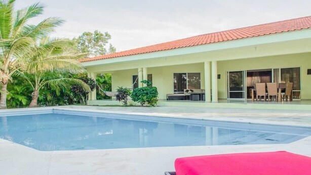 A modern building with a swimming pool, outdoor seating, and tropical landscaping. - Private Villa With Pool in Sosua for Large Groups (Sosúa)