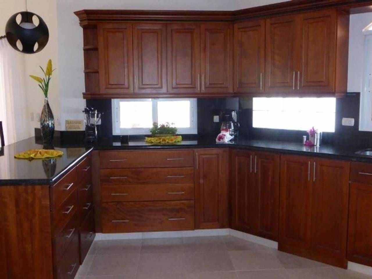 A kitchen with wooden cabinets, a black countertop, and a window.
