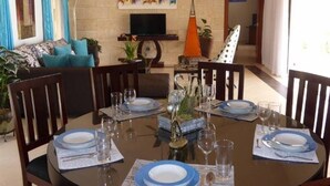 Un coin repas avec un mur en pierre, un téléviseur et une table à manger dressée pour six personnes.