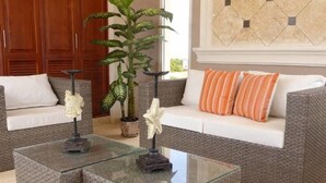 Un salon avec un canapé gris, deux tables basses carrées en verre et des objets de décoration.