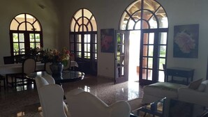 A spacious living room with a dining area, large arched windows, and a modern design. - Spacious Oceanfront Villa (Sosúa)