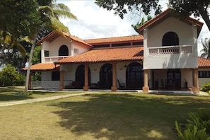 A two-story building with a red-tiled roof, multiple arches, and a balcony.