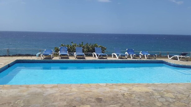 A swimming pool with lounge chairs and a view of the ocean. - Spacious Oceanfront Villa (Sosúa)