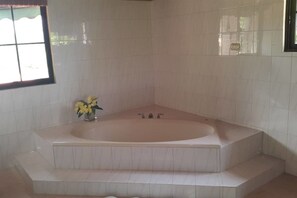 A bathroom with a freestanding bathtub, a small window, and a vase with flowers.