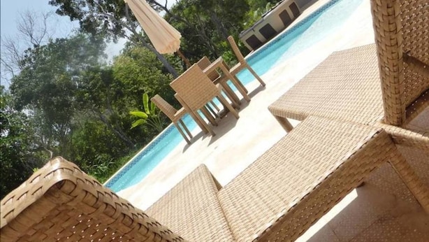 Zona junto a la piscina con muebles de mimbre y vista despejada al agua.