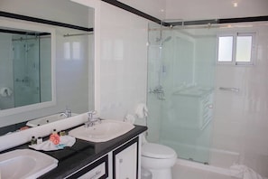 A modern bathroom with a glass-enclosed shower, a large mirror, and two sinks. - Romantic two Bedroom Deluxe Villa With all Modern Conveniences (Sosúa)