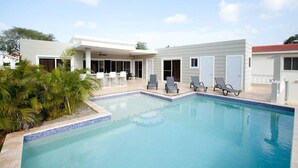 A swimming pool with lounge chairs and a covered patio area. - Stylish 3 Bedroom w/ Covered BBQ Area by the Pool (Sosúa)