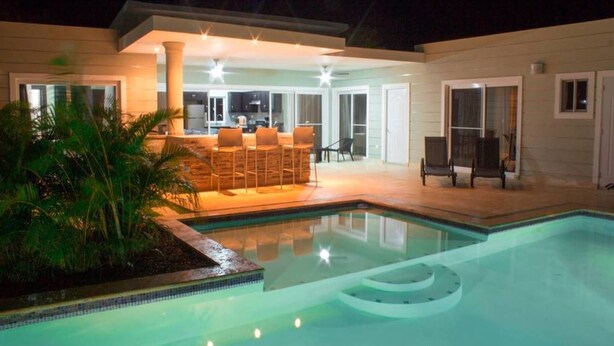 A modern house with a swimming pool, outdoor bar, and patio seating. - Stylish 3 Bedroom w/ Covered BBQ Area by the Pool (Sosúa)