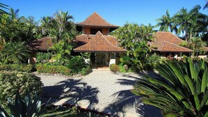 A two-story building with a tiled roof, surrounded by tropical vegetation and palm trees. - Villa Las Palmas Caribbean Family Vacation Rental (Cabarete)